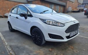 A White Ford Focus fully restored at Racers Paint and Panel - parked in a parking area outside their auto body shop