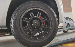 Front wheel of VW Amarok after custom high gloss black rim spray and brake calliper customisation at Racers Paint and Panel