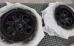 Two Tyres with rubber covered in plastic in the paint booth after paint respray at Racers Paint and Panel