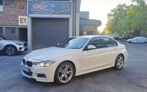 White BMW post auto body repair - fully restored in front of the Racers Paint and Panel autobody shop
